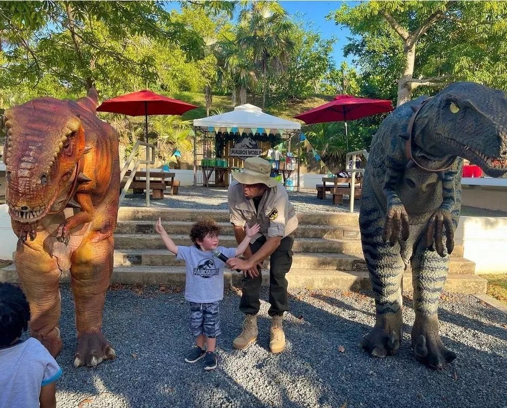 Niño interactuando con dos dinosaurios durante una actividad de Dino Aventuras